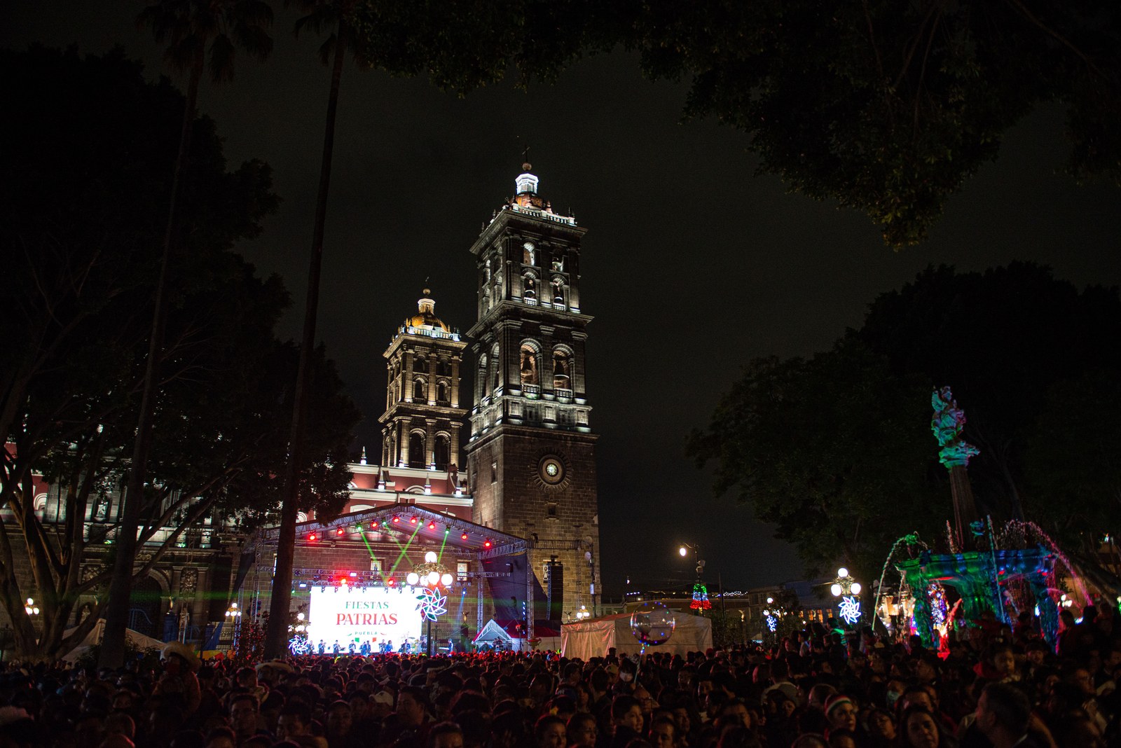 Evento cívico nocturno frente a la catedral, con escenario y público
